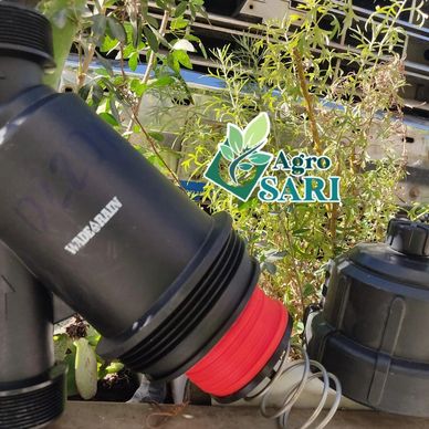 Filtro de agua agrícola junto a plantas verdes.