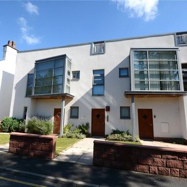 Modern white townhouses with large glass windows and wooden doors under a clear sky.