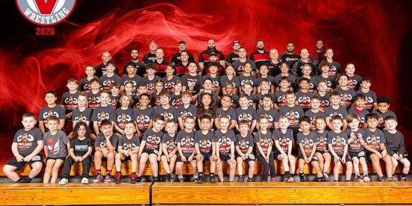Large group photo of a wrestling team in matching shirts.