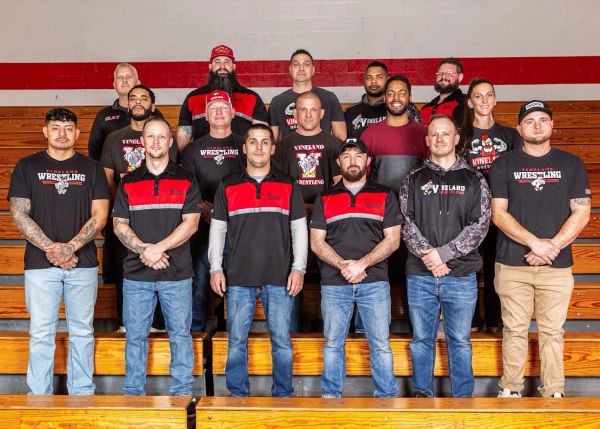 Group photo of a wrestling team in a gymnasium.