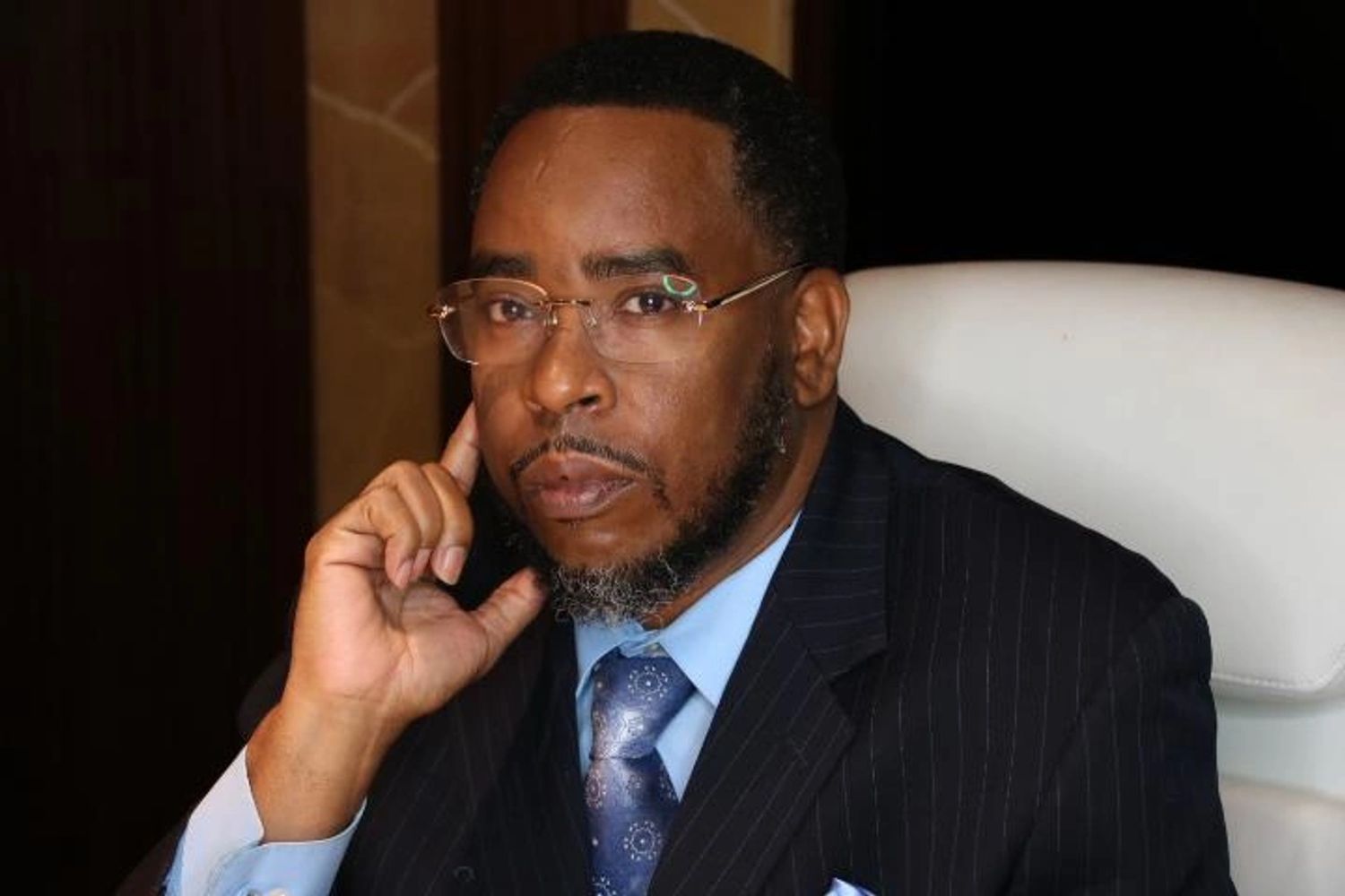 A man holds the hands on face with wearing Eyeglass and dress with looking ahead