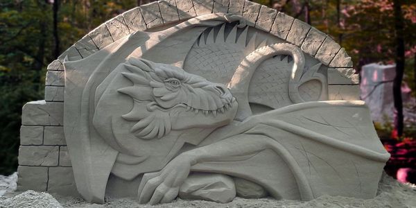a sand sculpture of a dragon set against New England fall foliage at a fall event in New Hampshire