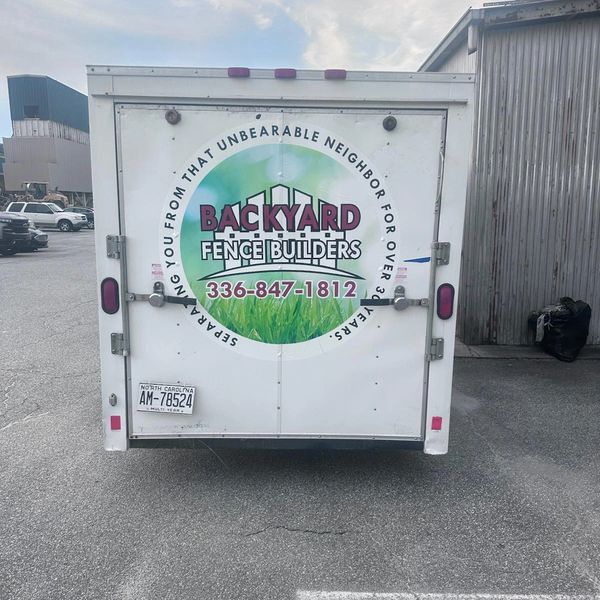 Backyard Fence Builders trailer with contact info and a humorous tagline.