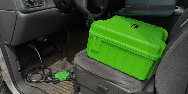 A green diagnostic device connected inside a vehicle.