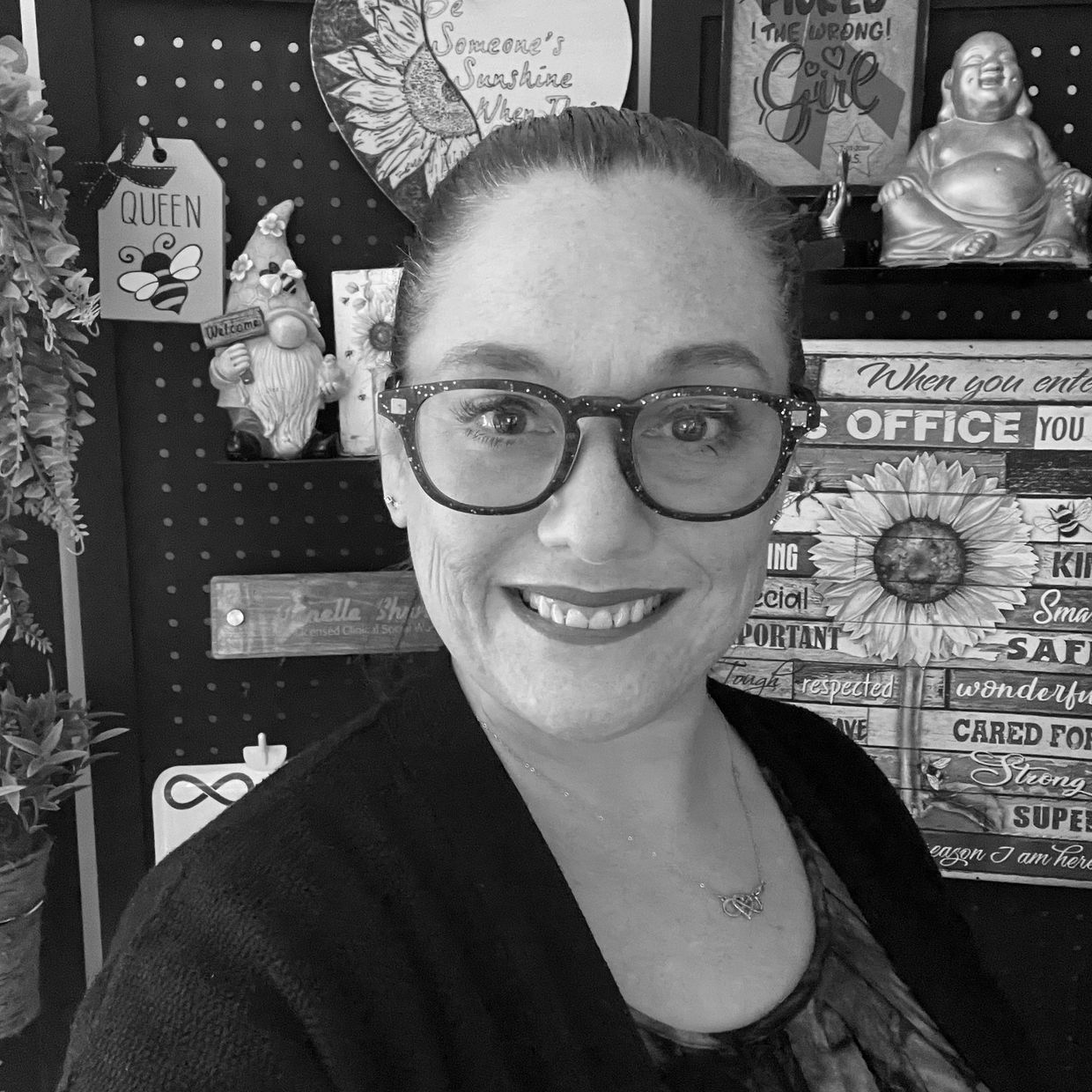 Smiling woman with glasses in a cozy, decorated room.