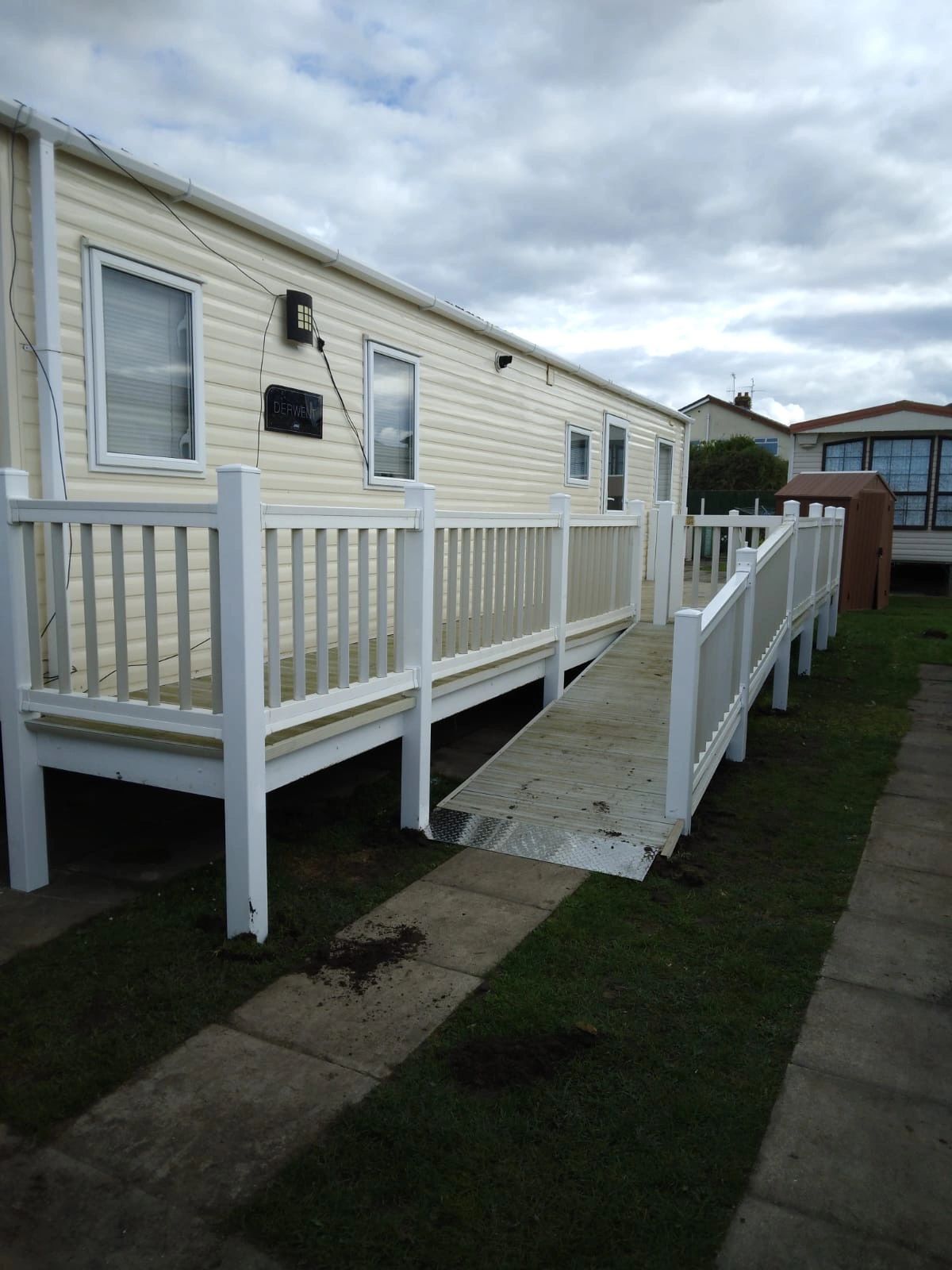 Jubilee, a white static caravan with white upvc ramped access with a gate at the top on to a large d