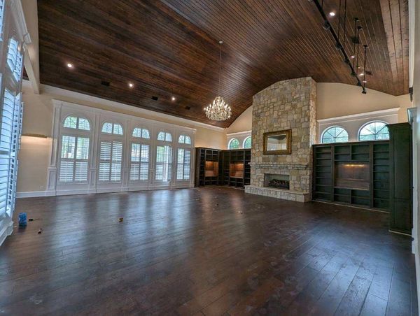 Spacious living room with high wooden ceiling and stone fireplace.