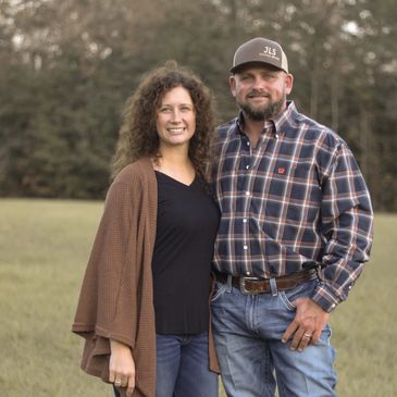 Smiling couple standing outdoors in casual fall attire.