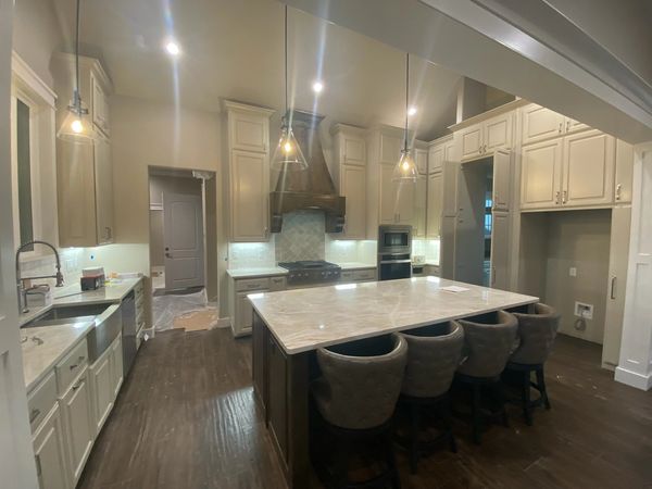 Spacious modern kitchen with marble island and pendant lighting.