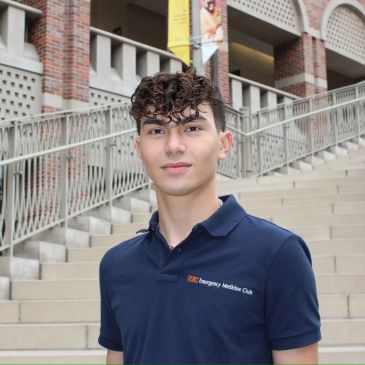 Young man in navy polo shirt standing outdoors on steps.