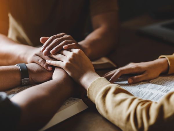 A group of people holding hands an reading from the bible