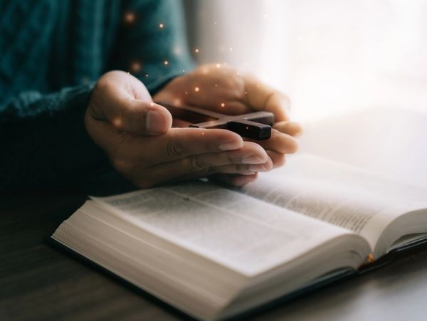 A person holding a cross on a bible