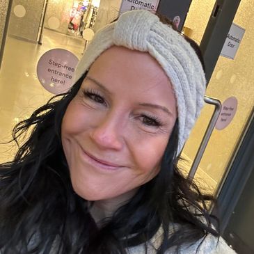 Smiling woman with dark hair wearing a cozy knit headband.