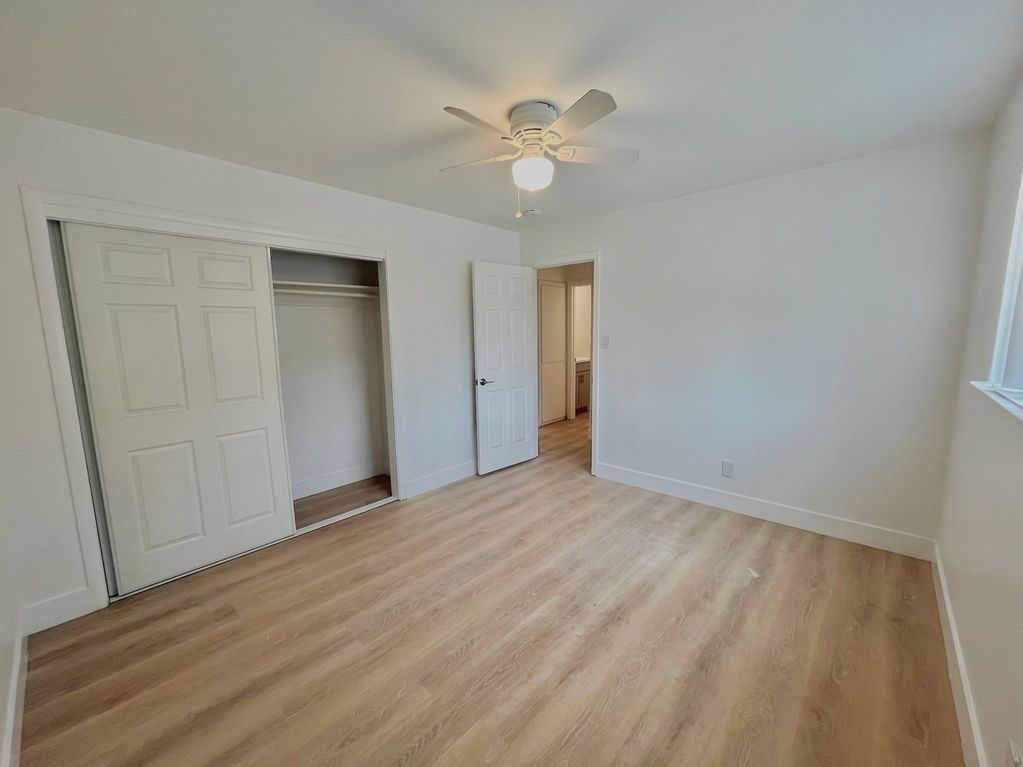 An unfurnished bedroom with a closet, light fixture, and new floors.