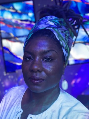 Close-up of a woman with a colorful headwrap in blue lighting.