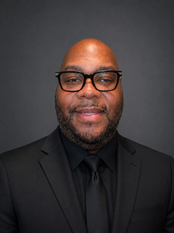 Professional portrait of a man in a black suit and glasses, Chappelle 
