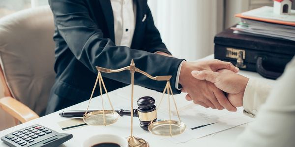 Businessman shaking hands to seal a deal with his partner lawyers or attorneys discussing