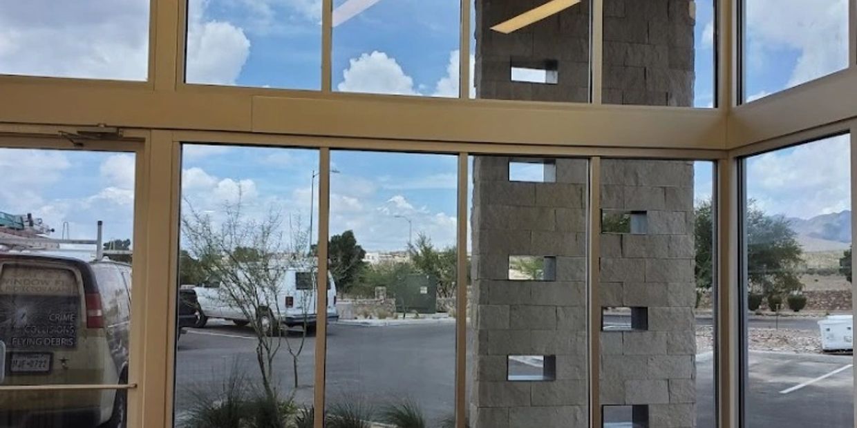 View through large glass windows showing parking lot and cloudy sky.