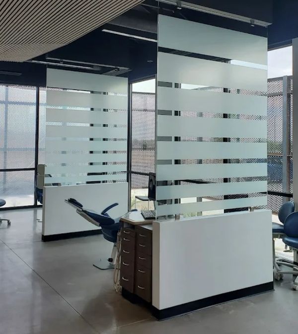 Modern dental clinic with frosted glass partitions and dental chairs.