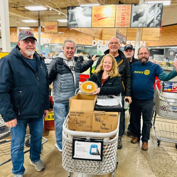 Group of six people posing with food in a grocery store.