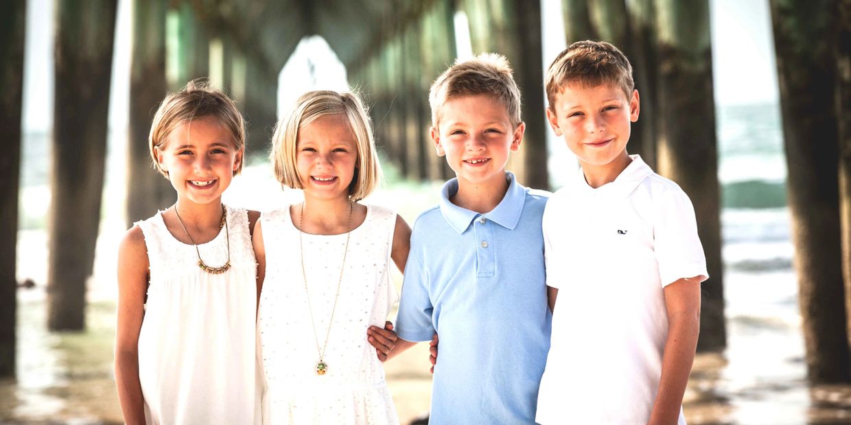 Timeless family beach portrait of 4 family teenagers having their photo taken under the pier