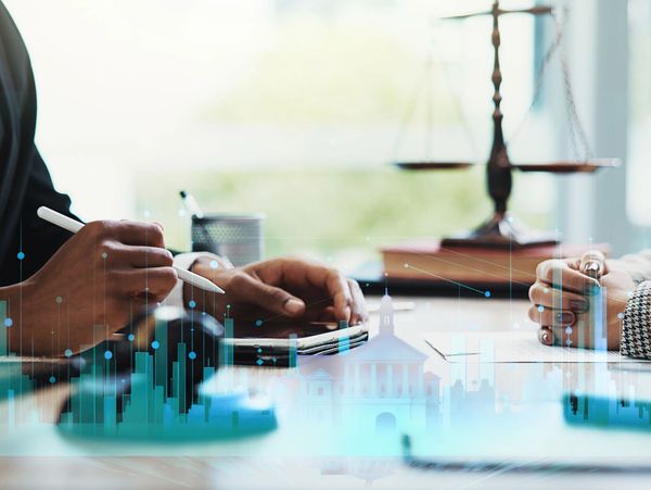 A male and female lawyer discuss legal documents with an overlay of building graphics.

