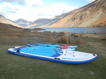 Family board and red paddle boards together at the lakeshore. 