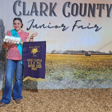 Girl holds eggs and award banner at Clark County Junior Fair.