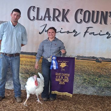 Two people with a turkey and a banner at a county fair.