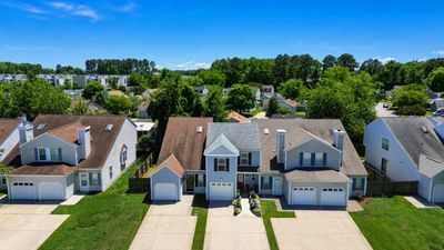 Row of suburban houses with garages and well-maintained lawns under a clear blue sky.