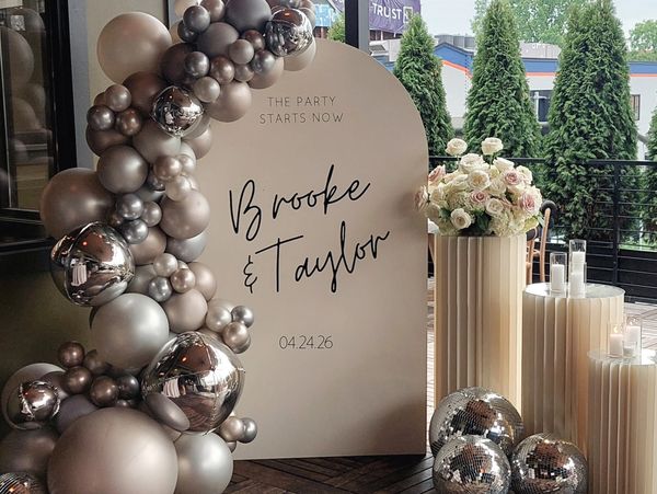 Elegant party sign with balloons and flowers.