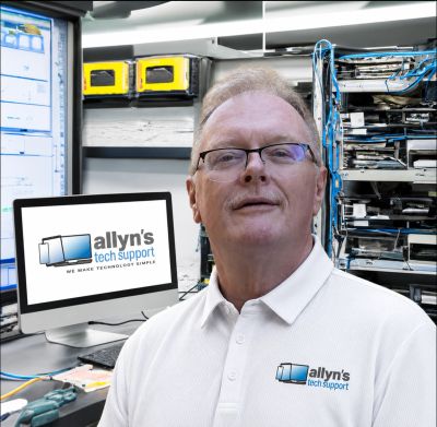 Tech support professional in office with computer and server racks.