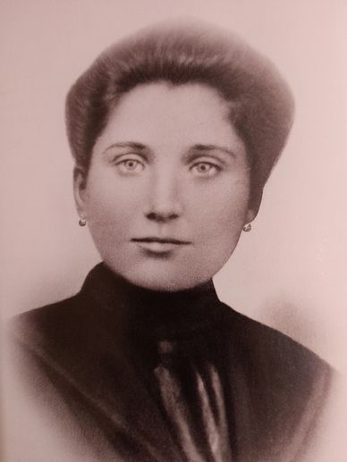 Black and white portrait of a woman with earrings and a high-neck garment.