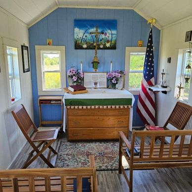 Small chapel interior with altar, wooden benches, and an American flag.