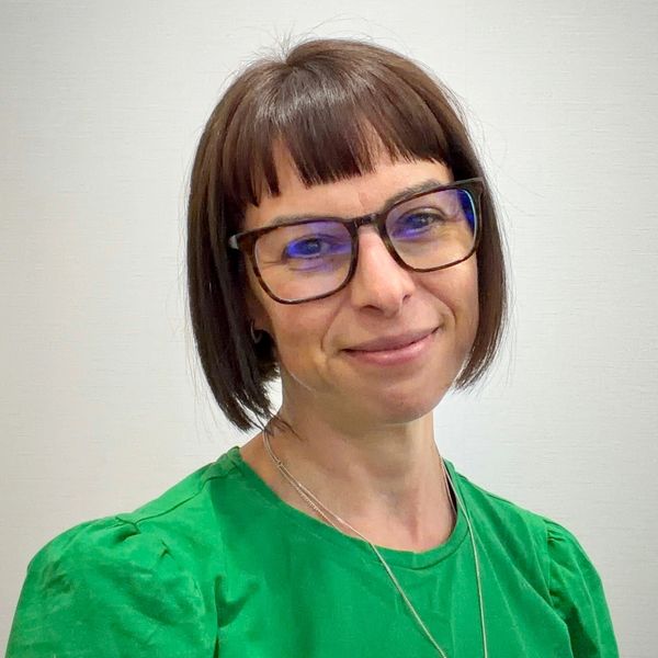 Woman with glasses and short brown hair smiling.