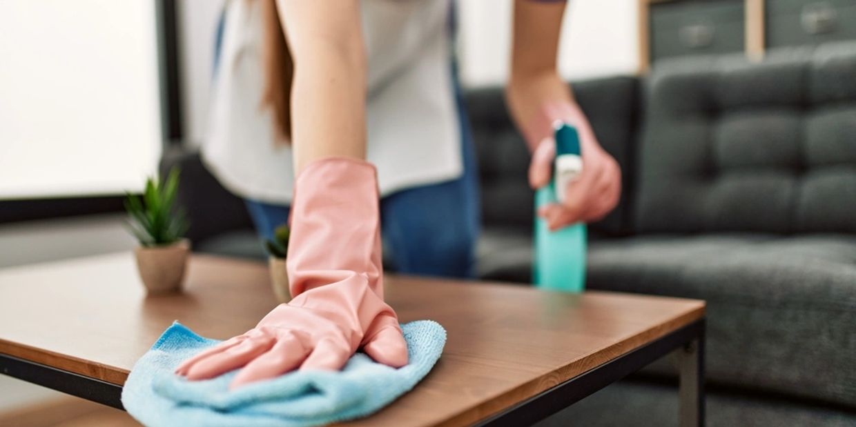 Woman cleaning table using rag and diffuser at home. 