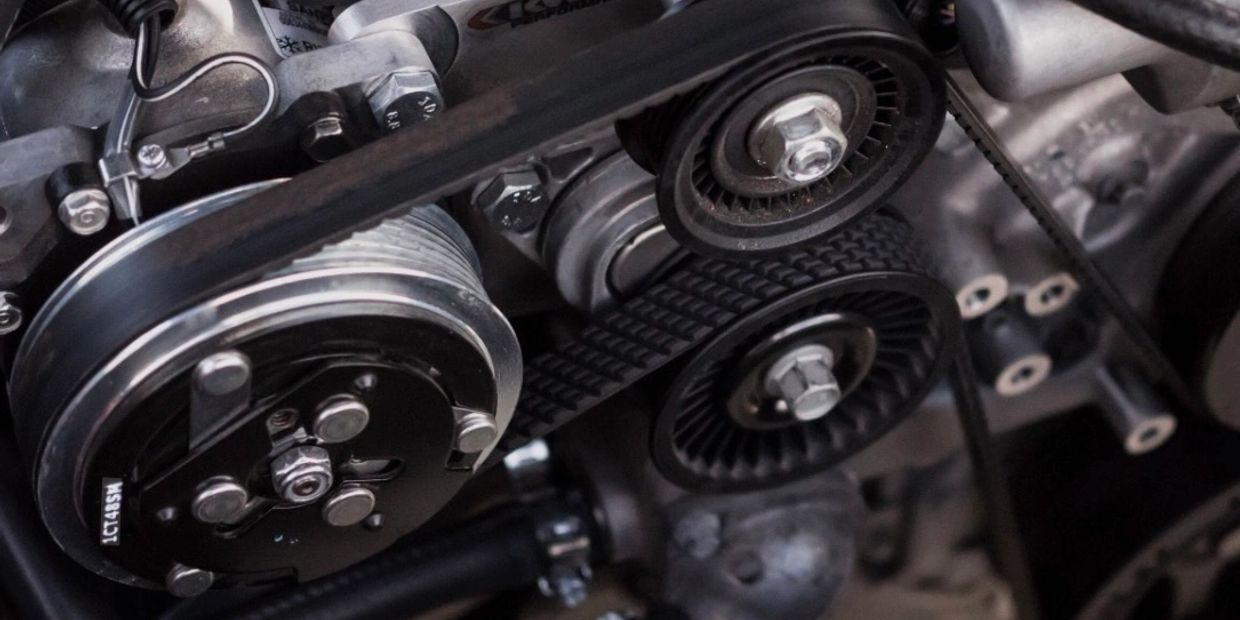 Close-up of a car engine's belt and pulley system.