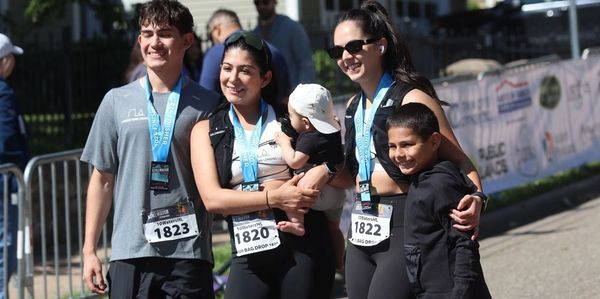 a group of 5 people that just got done running a marathon. They are smiling and happy. 