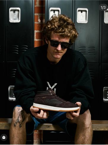 Man in sunglasses holding a DILO sneaker in a locker room.