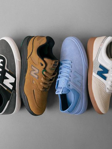 Four New Balance sneakers in different colors arranged on a gray surface.
