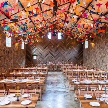 colourful barn set up as a dinning space with tables and chairs.