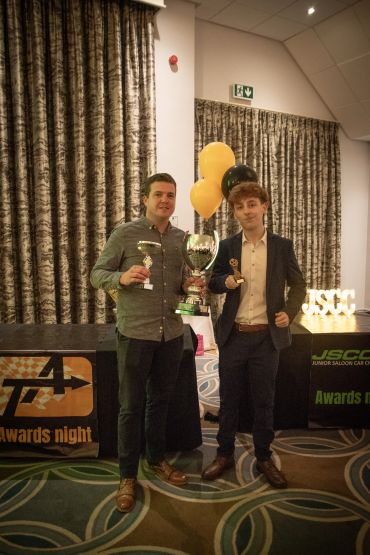 Two men holding trophies at an awards night event.