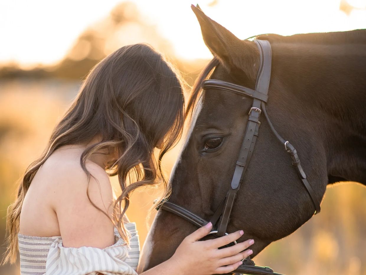 Girl placing her head on her horse's head.