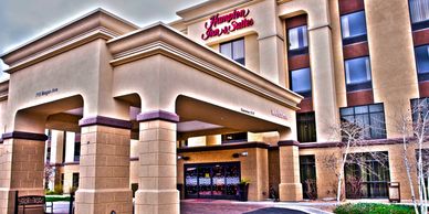 Exterior view of Hampton Inn &amp; Suites hotel entrance with clear signage.