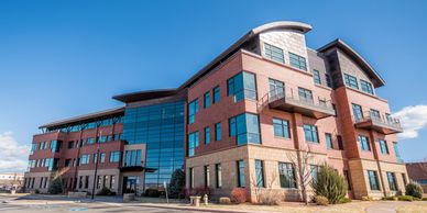Modern office building with glass and brick facade under a clear blue sky.