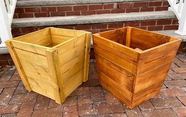 Two wooden planter boxes on a brick patio near steps.