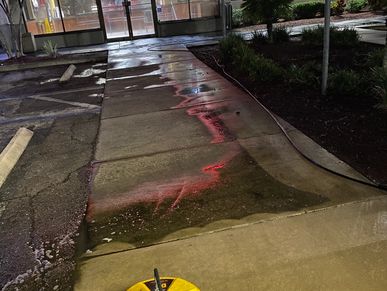 Wet sidewalk with red light reflections at night.