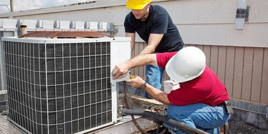 Two technicians working on an HVAC unit outdoors