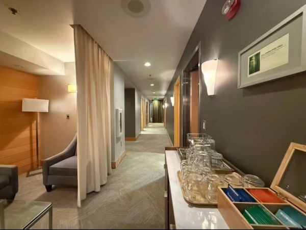 Hotel hallway with seating area and refreshment station.