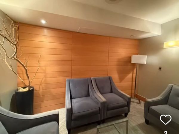 Modern lounge with gray armchairs and warm wooden paneling.